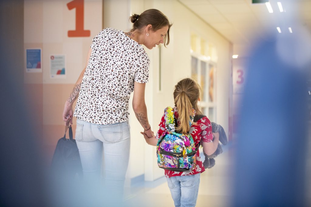 Moeder pakt kind bij de hand. Ze lopen door de gang